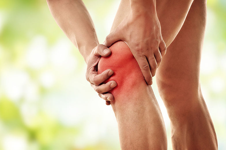 Abbildung einer stehenden Person mit Fokus auf die Beine. Schmerzen im Knie durch Rotfärbung dargestellt.